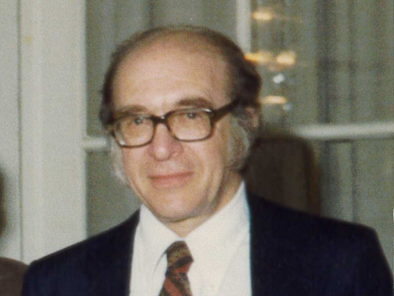 Older man with glasses, tie and blue suit coat