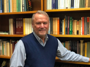 Bruce Caldwell stands in front of shelves of books.