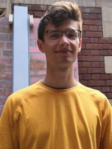 Young white male with glasses wearing a yellow tshirt